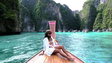 Bir kadın olarak Pileh Lagoon 'un nefes kesen manzarasını tecrübe edin. Tayland' ın Koh Phi şehrinde sarp kayalıklar ve canlı turkuaz sularla çevrili geleneksel uzun kuyruklu bir teknede dinleniyor..