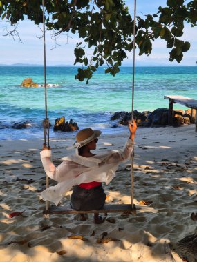Tayland, Rayong 'daki Klaeng sahilinin berrak sularına bakan bir ağacın altında salıncağın keyfini çıkarıyorum. Rahatlamak ve gençleşmek için mükemmel bir kaçış. Koh Munnork
