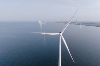 Hollanda, Flevoland yakınlarındaki sakin denizin üzerinde duran sayısız rüzgar türbininin manzarası. Denizaşırı yel değirmeni çiftliği, Hollanda 'da yeşil enerji