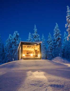Karlı bir arazide, içeriden aydınlatılmış büyüleyici bir kulübe Akaslompolo 'daki kış sükunetinin özünü yakalar. Gece, yıldızlarla parıldayıp-parıldar ve (gökyüzünün) düzeni bozulur..