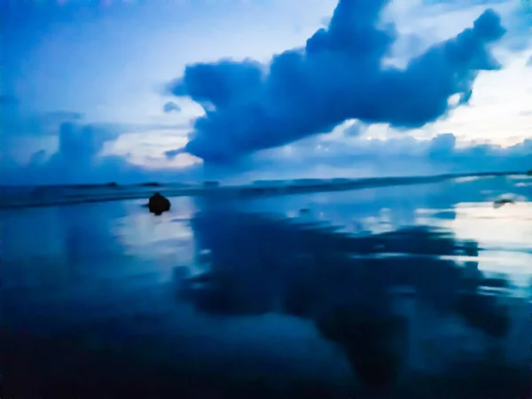 The beauty of India\'s long sea at sunset. Black clouds in the blue sky and the reflection of red sunlight.