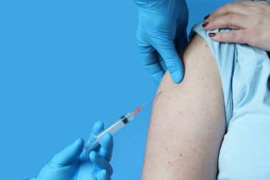 Elinde şırınga tutan doktor kadın hastanın omzuna kovid 19 aşısı yapıyor. Corona virüs tedavi konsepti, görünümü kapat.