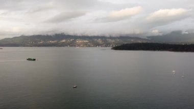 Vancouver Stanley Parkı yakınlarındaki küçük yatın ve büyük kargo gemisinin havadan görüntüsü.