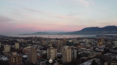 Gün batımında Vancouver 'da dağ ve kargo gemisi olan evlerin havadan görüntüsü.