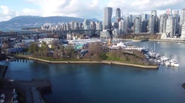 Şehir merkezinde Vancouver ve Granville adasının önünde güneşli bir günde dağlar.