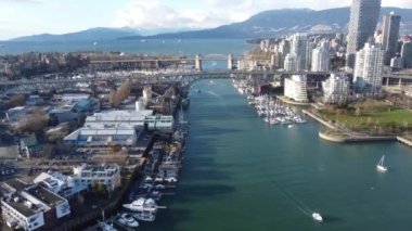Vancouver 'daki derenin üzerinden uç. Arka plandaki dağlar ve körfezdeki kargo gemileriyle.