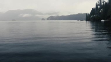 Yağmurlu bir günde orman ve dağlarla çevrili körfezdeki berrak sular.