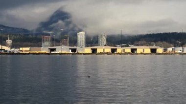 Gemi terminali ve yükleme rıhtımı arkasında bulutlarla kaplı dağlarla