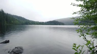 Bulutlu bir günde gölün zamanı yeşil tepelerle çevrili.
