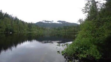 Kanada gölü, balıkçı teknesiyle zamanlaması, yeşil dağda hareket eden bulutlar.