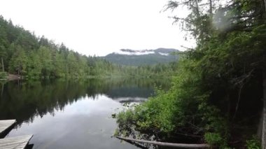 Yağmurlu bir günde, orman ve yeşil dağlarla çevrili gölün zamanı.