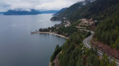 Dağ kenarındaki kavisli otoyolun hava manzarası ve Kanada 'daki sakin koy suları