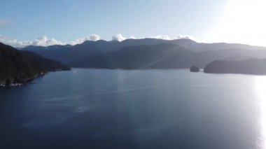 Sakin su ve tepelerdeki yeşil ladin ormanının havadan görünüşü.