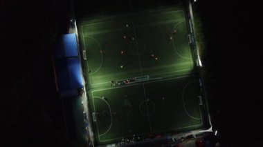 İki futbol sahasının yukarıdan görünüşü ve karanlık bir akşamda oynayan takımlar.