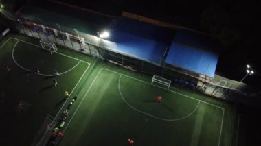 Gece futbol sahasının havadan görünüşü. Amigoluk takımları ve kaleciler bekliyor.