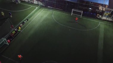 Küçük bir stadyumda gece boyunca oynayan futbol takımlarının hava görüntüsü.