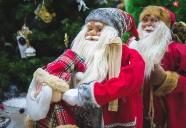 Rus Noel Baba 'nın kırmızı elbiseli üç bebeği Noel ağacının arka planında.