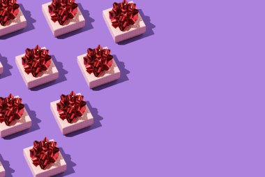 Mor arka planda kırmızı yay desenli bir hediye.