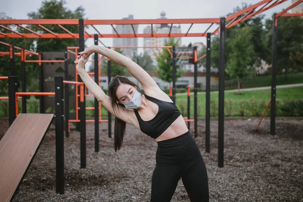 Młoda kobieta uprawia sport na placu zabaw w masce — Zdjęcie stockowe