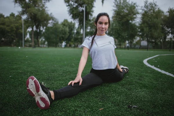 Una giovane donna fa la gamba divisa nel parco giochi — Foto Stock