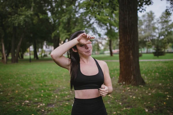 Wanita muda lelah setelah latihan menghapus keringat olahraga di taman — Stok Foto