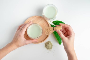 Genç kadın elinde çay çırpmak için çırpıcıyı tutuyor. Çay seremonisi. Matcha yeşil çay tozu. Organik yeşil çay yaprağı, beyaz arka planda izole edilmiş, organik ürün, gelenek açısından sağlıklı.