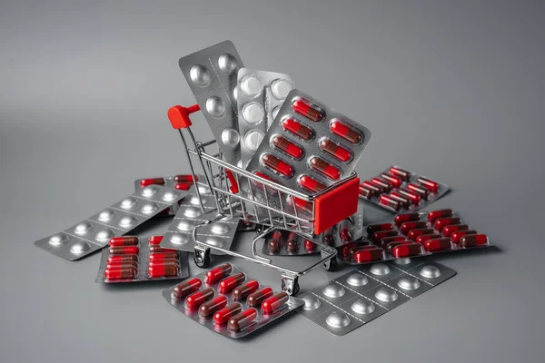 Tablets in shopping basket. Red pills on a pink background. Pills and capsules in shopping cart close-up. oncept of buying medicines online, delivery of medicines during an epidemic.