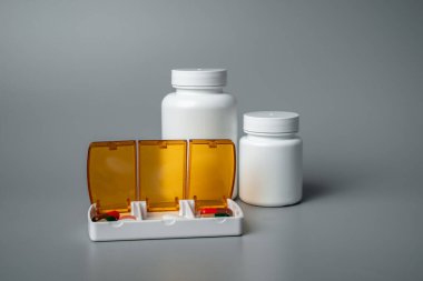 Gri arka planda haplar olan tablet kutusu. Yarın için tabletler, öğle ve akşam yemeği. Hastalık önleme