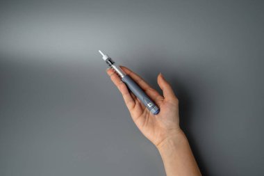 Genç bir kadın insülin şırıngası tutuyor. Diyabet endokrin sisteminin bir hastalığıdır. Gri arka planda bir şırınga.