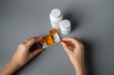 Gri arka planda haplar olan tablet kutusu. Yarın için tabletler, öğle ve akşam yemeği. Hastalık önleme