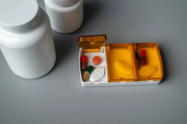 Gri arka planda haplar olan tablet kutusu. Yarın için tabletler, öğle ve akşam yemeği. Hastalık önleme
