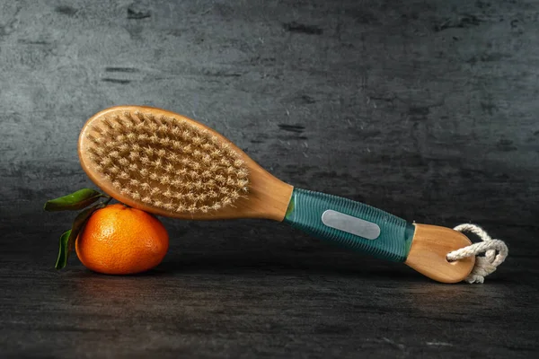 Anti-cellulite body massage brush. Brush and tangerine on a dark background. Cactus exfoliating brush for body care