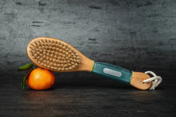 Anti-cellulite body massage brush. Brush and tangerine on a dark background. Cactus exfoliating brush for body care