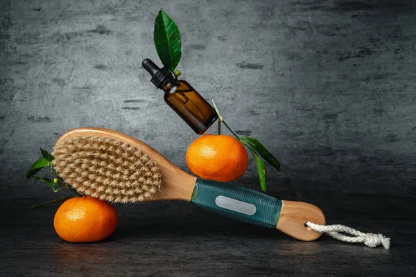 Anti-cellulite body massage brush. Brush and tangerine on a dark background. Cactus exfoliating brush for body care