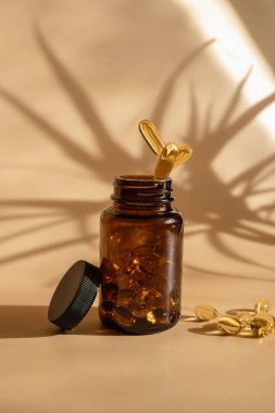 Haplar kavanoza düşer. Havalanma stili. Bej arkaplanda Omega 3 tabletleri.