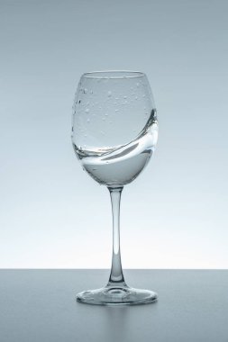 Gri arka planda bir bardakta su damlası.