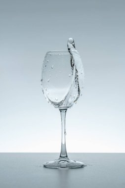 Gri arka planda bir bardakta su damlası.