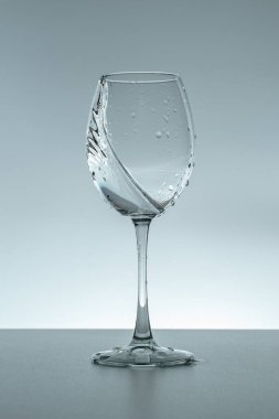 Gri arka planda bir bardakta su damlası.