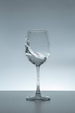 Gri arka planda bir bardakta su damlası.