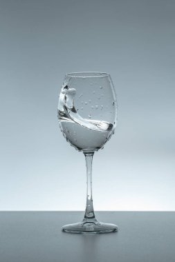 Gri arka planda bir bardakta su damlası.