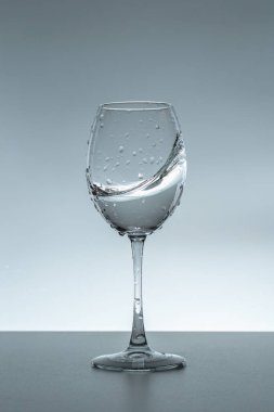 Gri arka planda bir bardakta su damlası.