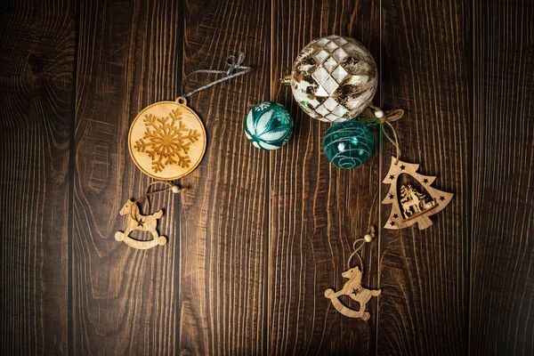 New Year's decor on a wooden background. Fir branches, Christmas balls and wooden toys. Cozy home. Place for the text. View from above