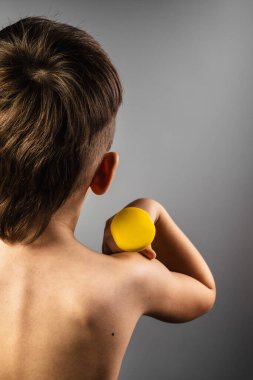 Çocuk elinde bir dambıl tutuyor. Sporcu fitness ile meşgul. Bir adamın güçlü kaslı sırtı.