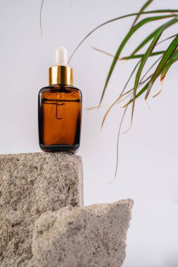 Esans şişesi pedistalde. Beyaz arka planda losyon. Cilt sağlığı için kozmetik. Aromo Petrol. C vitamini serumları, Unisex kozmetik ürünleri. Model. 