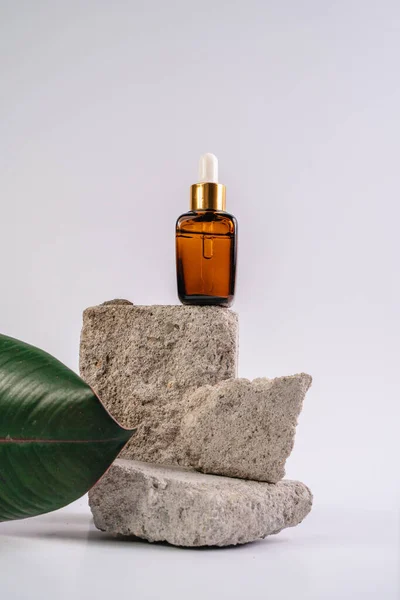 Esans şişesi pedistalde. Beyaz arka planda losyon. Cilt sağlığı için kozmetik. Aromo Petrol. C vitamini serumları, Unisex kozmetik ürünleri. Model. 