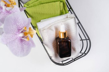 Aroma yağı banyodaki havlunun üzerinde duruyor. Mor orkideler. Eko Kozmetik