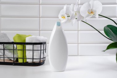 Beyaz fayans zemininde şampuan. Duş jeli ve banyoda orkideler. Cilt sağlığı için kozmetik. Logon için bir model. Kopya alanı olan banyo modeli. Şampuan şişesi ya da duş jeli.
