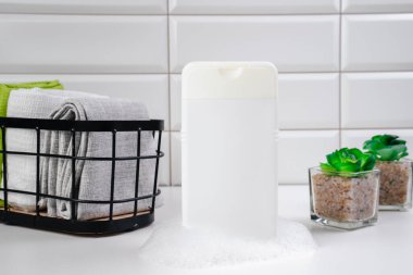 Beyaz fayans zemininde şampuan. Duş jeli ve banyoda orkideler. Cilt sağlığı için kozmetik. Logon için bir model. Kopya alanı olan banyo modeli. Şampuan şişesi ya da duş jeli.