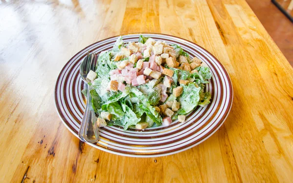 ベーコンと木のテーブルに緑のシーザー サラダ — ストック写真