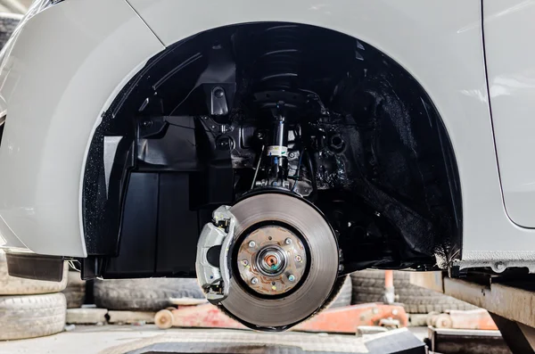 Travão de disco dianteiro no carro em processo de substituição de pneus novos. O — Fotografia de Stock